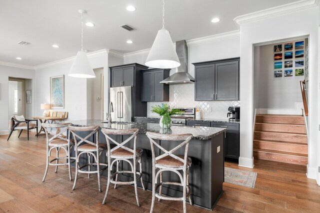 92 Maple St, Santa Rosa Beach, FL 32459 - kitchen featuring wall chimney exhaust hood, high end refrigerator, a center island with sink, light stone countertops, and a breakfast bar area