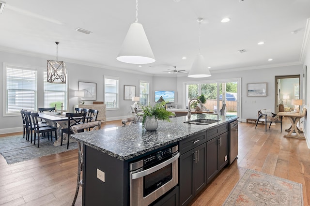 92 Maple St, Santa Rosa Beach, FL 32459 - kitchen featuring light wood-type flooring, stainless steel appliances, crown molding, dark stone counters, and a ceiling fan