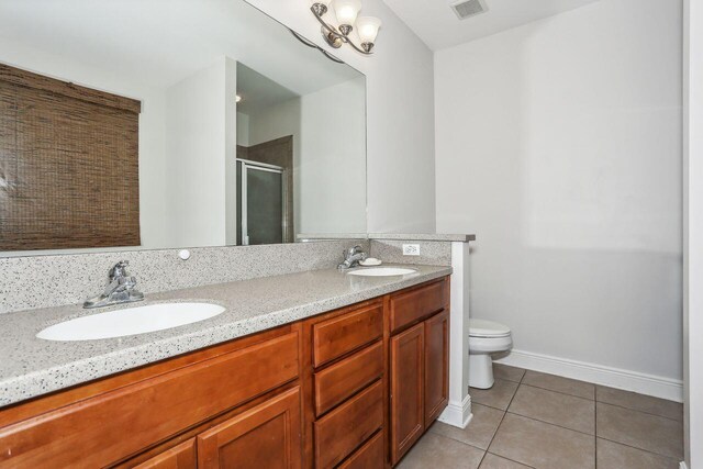 312 Scotch Pine Ln, Crestview, FL 32536 - full bathroom with tile patterned floors, double vanity, a stall shower, toilet, and baseboards