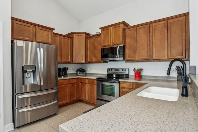 312 Scotch Pine Ln, Crestview, FL 32536 - kitchen with stainless steel appliances, a sink, lofted ceiling, light tile patterned floors, and brown cabinets