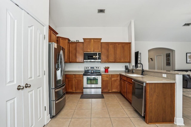 312 Scotch Pine Ln, Crestview, FL 32536 - kitchen featuring stainless steel appliances, a sink, arched walkways, light tile patterned flooring, and a peninsula