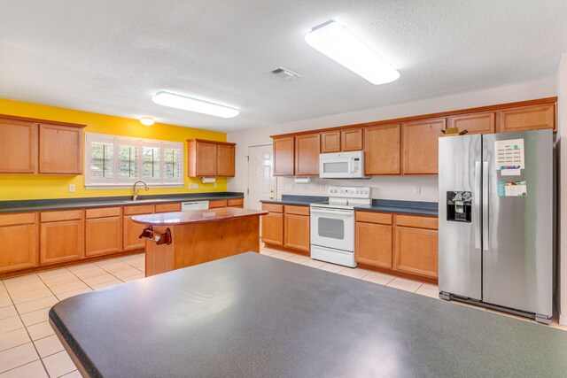 207 E Shipwreck Rd, Santa Rosa Beach, FL 32459 - kitchen with white appliances, a sink, light tile patterned flooring, a kitchen island, and a textured ceiling