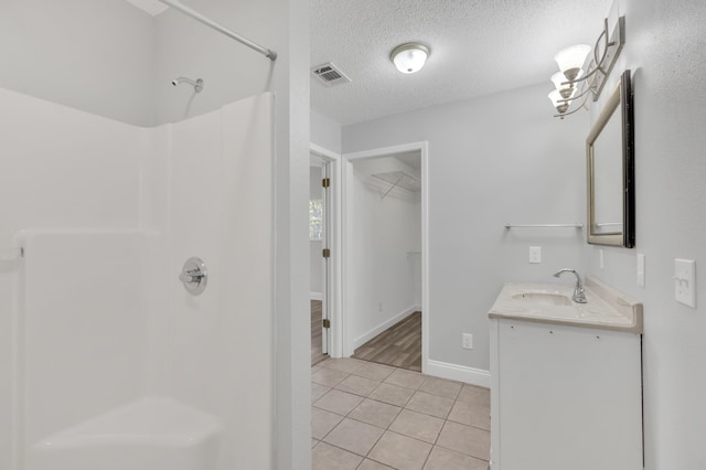 319 Jones Rd, Crestview, FL 32536 - bathroom featuring a shower, tile patterned flooring, a textured ceiling, a walk in closet, and vanity