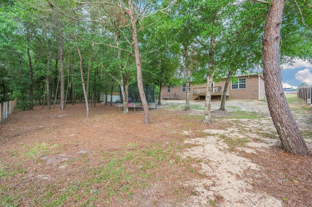41 S Hidden Lakes Trl, Defuniak Springs, FL 32433 - view of yard with a trampoline, a wooden deck, and fence