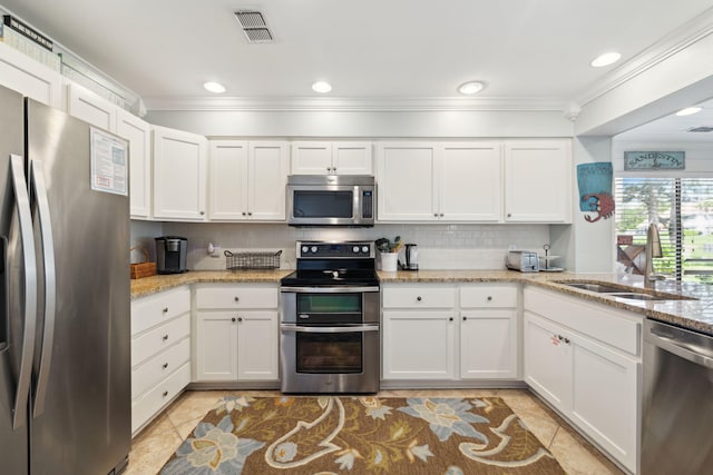 5144 Beachwalk Cir, Miramar Beach, FL 32550 - kitchen featuring appliances with stainless steel finishes, a sink, ornamental molding, light tile patterned floors, and white cabinetry