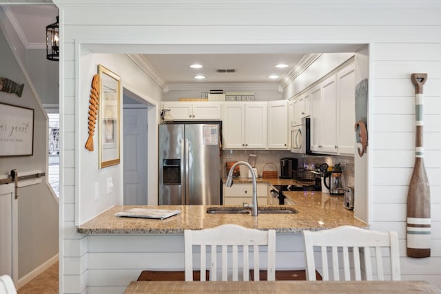 5144 Beachwalk Cir, Miramar Beach, FL 32550 - kitchen with appliances with stainless steel finishes, a sink, a peninsula, light stone counters, and ornamental molding