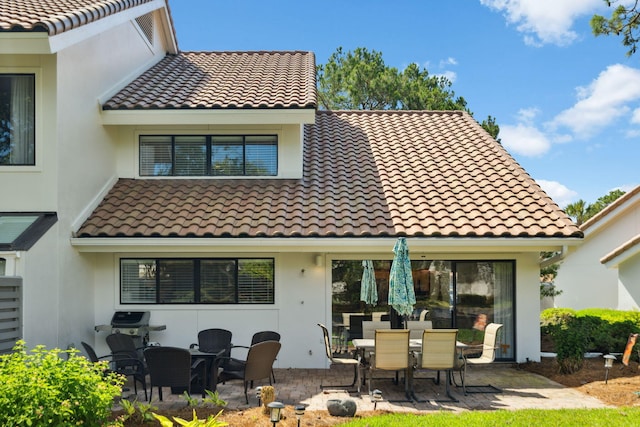 5144 Beachwalk Cir, Miramar Beach, FL 32550 - rear view of property featuring a tiled roof, stucco siding, a patio, and outdoor dining space