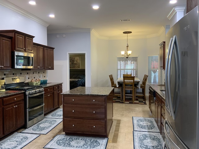 kitchen with appliances with stainless steel finishes, a chandelier, crown molding, backsplash, and dark stone counters