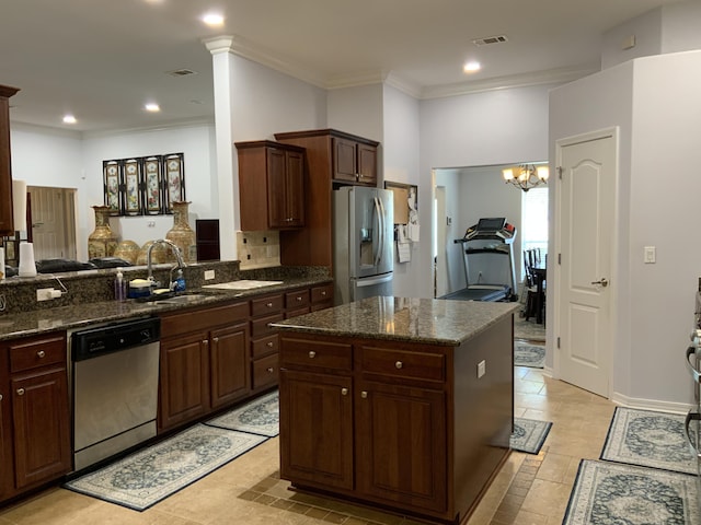 kitchen featuring appliances with stainless steel finishes, a sink, dark stone counters, tasteful backsplash, and a center island