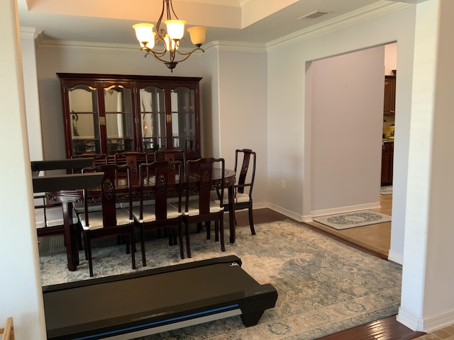 dining room featuring a chandelier, crown molding, baseboards, and wood finished floors