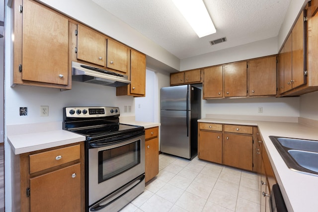 136 Midland Ct, Niceville, FL 32578 - kitchen with appliances with stainless steel finishes, under cabinet range hood, a textured ceiling, light countertops, and brown cabinetry