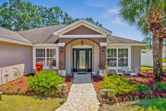 100 Kensington Cir, Panama City Beach, FL 32413 - view of exterior entry featuring a shingled roof, stucco siding, and fence