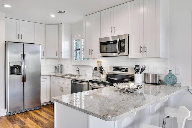 3799 E County Highway 30a # H-4, Santa Rosa Beach, FL 32459 - kitchen with stainless steel appliances, a sink, a peninsula, light stone countertops, and white cabinetry