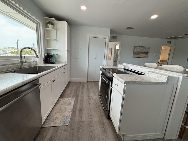 101 Barbados Dr, Cape San Blas, FL 32456 - kitchen featuring stainless steel appliances, a sink, a kitchen island, light wood finished floors, and white cabinetry