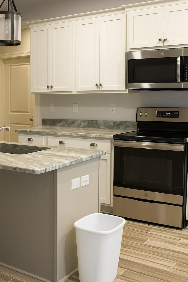 95 Santana Dr, Santa Rosa Beach, FL 32459 - kitchen featuring appliances with stainless steel finishes, white cabinets, light wood-type flooring, and light stone countertops
