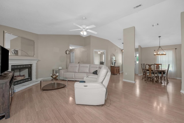 712 Riva Ridge Dr, Crestview, FL 32539 - living room with vaulted ceiling, light wood-style floors, a ceiling fan, a fireplace with raised hearth, and a chandelier