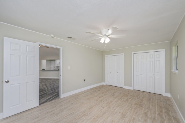 6859 Bill Lundy Rd, Laurel Hill, FL 32567 - unfurnished bedroom featuring light wood-type flooring, two closets, baseboards, and ceiling fan