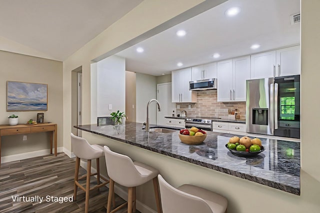6859 Bill Lundy Rd, Laurel Hill, FL 32567 - kitchen with stainless steel appliances, dark stone counters, dark wood finished floors, tasteful backsplash, and white cabinets