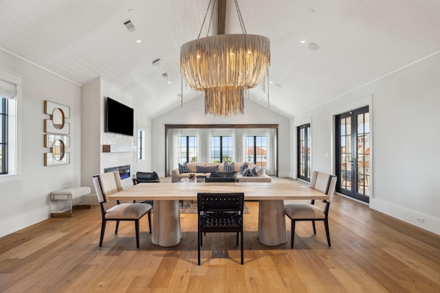 5012 W County Highway 30a, Santa Rosa Beach, FL 32459 - dining room featuring light wood-style floors, a glass covered fireplace, baseboards, lofted ceiling, and a chandelier