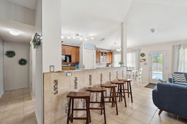 187 Sandy Cay Dr, Miramar Beach, FL 32550 - kitchen with brown cabinetry, light tile patterned floors, a breakfast bar, a textured ceiling, and baseboards