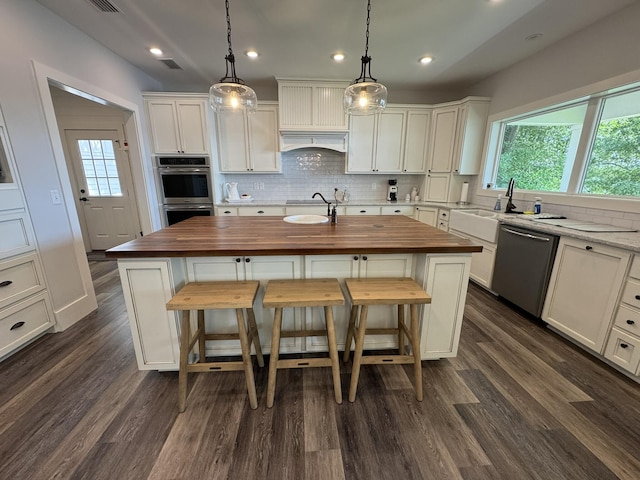 275 Lake Holley Cir, Defuniak Springs, FL 32433 - kitchen with butcher block counters, appliances with stainless steel finishes, a kitchen island with sink, healthy amount of natural light, and recessed lighting