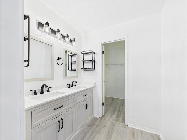 1000 Bay Dr Unit 524, Niceville, FL 32578 - bathroom with wood finished floors, double vanity, a walk in closet, and baseboards