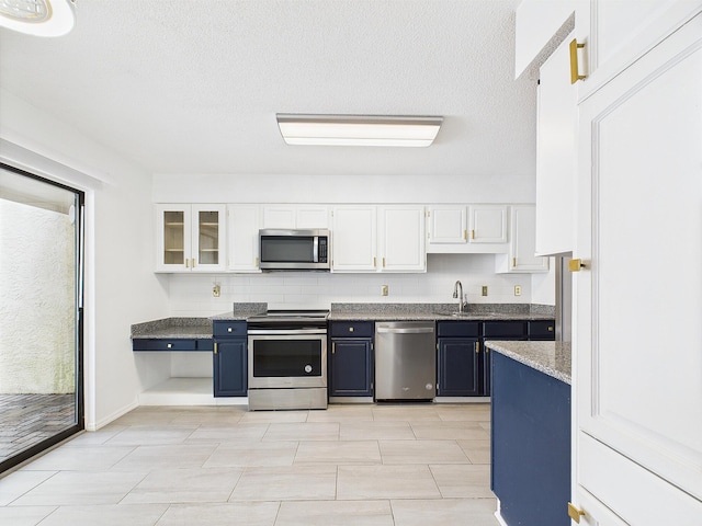 1000 Bay Dr Unit 524, Niceville, FL 32578 - kitchen featuring appliances with stainless steel finishes, white cabinetry, glass insert cabinets, a sink, and tasteful backsplash