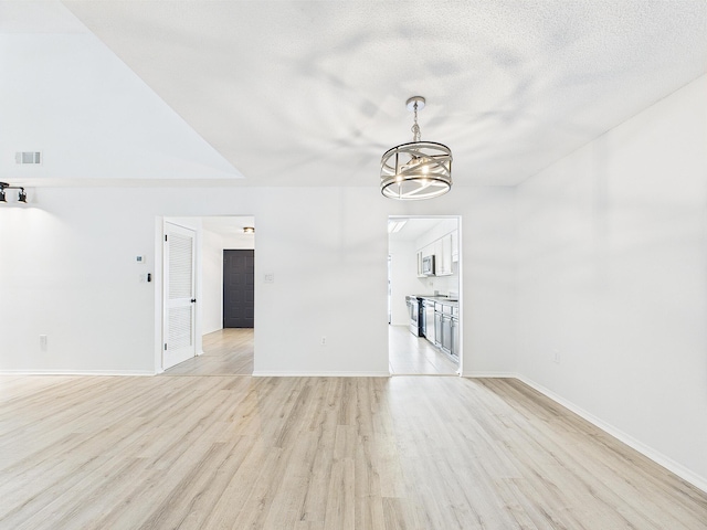 1000 Bay Dr Unit 524, Niceville, FL 32578 - unfurnished living room featuring light wood-type flooring, a chandelier, baseboards, and a textured ceiling