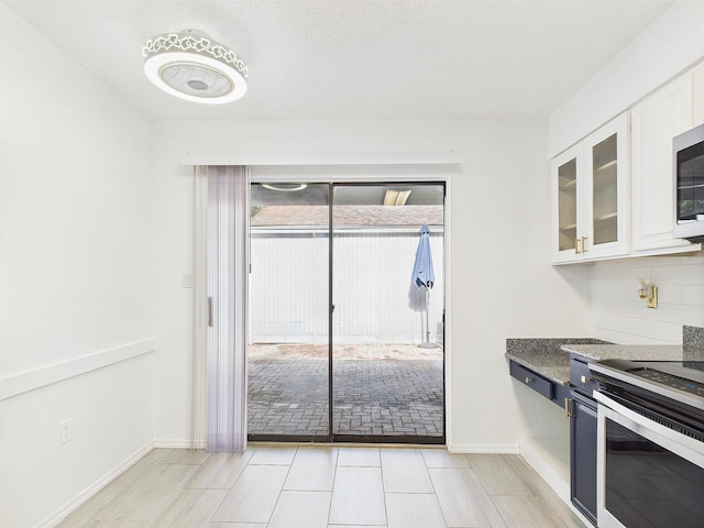 1000 Bay Dr Unit 524, Niceville, FL 32578 - kitchen featuring stainless steel electric stove, white cabinetry, glass insert cabinets, dark stone countertops, and baseboards