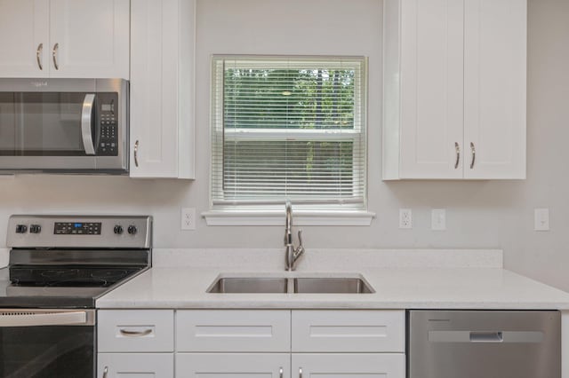 192 S Norwood Rd, Defuniak Springs, FL 32435 - kitchen featuring appliances with stainless steel finishes, a sink, white cabinets, and light stone countertops