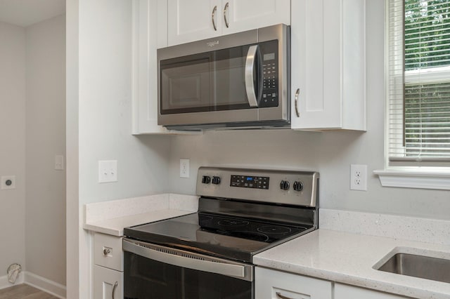192 S Norwood Rd, Defuniak Springs, FL 32435 - kitchen with appliances with stainless steel finishes, healthy amount of natural light, white cabinets, and light stone countertops