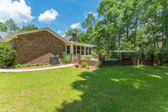 6087 Terrace Ln, Crestview, FL 32536 - rear view of house featuring a sunroom, brick siding, central AC, and a yard