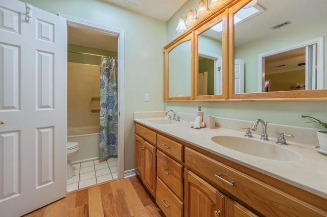 6087 Terrace Ln, Crestview, FL 32536 - full bathroom with double vanity, toilet, wood finished floors, and shower / bath combo with shower curtain