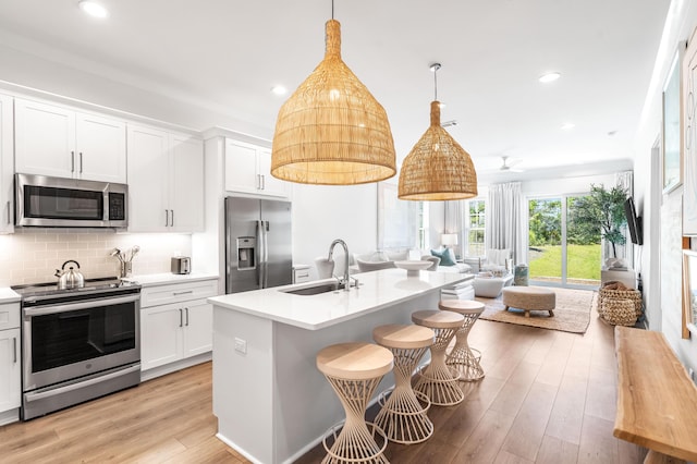 70 Martha S Ln # 2-101, Santa Rosa Beach, FL 32459 - kitchen with stainless steel appliances, a sink, open floor plan, light wood finished floors, and light countertops