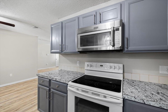 1008 Aspen Ct, Fort Walton Beach, FL 32547 - kitchen with white electric range oven, stainless steel microwave, gray cabinets, light wood-style flooring, and a textured ceiling