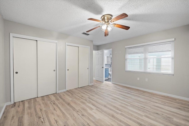 1008 Aspen Ct, Fort Walton Beach, FL 32547 - unfurnished bedroom featuring two closets, light wood-type flooring, a textured ceiling, baseboards, and ensuite bathroom