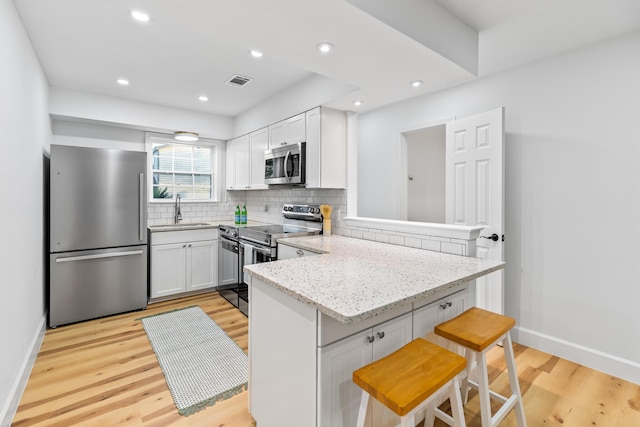 43 Summer Haven Trl Unit 3, Miramar Beach, FL 32550 - kitchen featuring stainless steel appliances, a peninsula, a sink, light wood-style floors, and tasteful backsplash