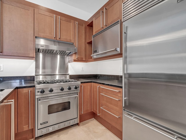 9201 Market St Inn Unit 159, Miramar Beach, FL 32550 - kitchen featuring premium appliances, brown cabinetry, under cabinet range hood, and light tile patterned flooring