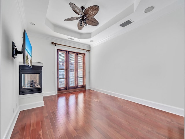 9201 Market St Inn Unit 159, Miramar Beach, FL 32550 - unfurnished living room featuring a raised ceiling, a ceiling fan, a multi sided fireplace, wood finished floors, and baseboards