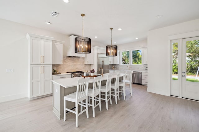 55 May Dr, Santa Rosa Beach, FL 32459 - kitchen with premium range hood, stainless steel appliances, backsplash, a kitchen island with sink, and light countertops