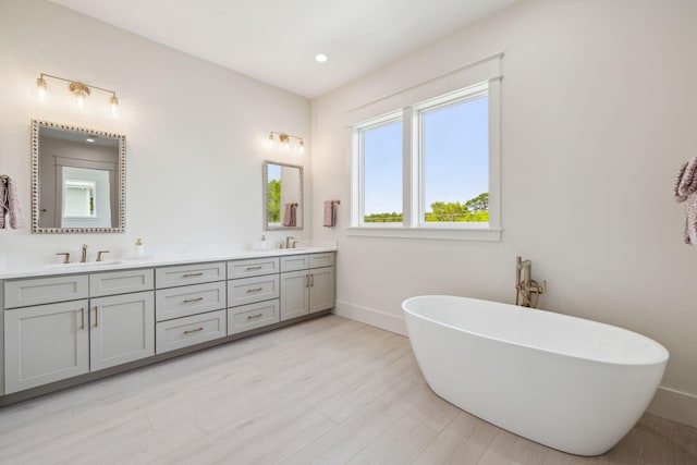 55 May Dr, Santa Rosa Beach, FL 32459 - full bathroom featuring baseboards, double vanity, a freestanding bath, wood finished floors, and recessed lighting