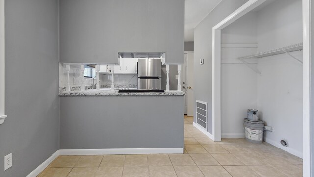 1737 S County Highway 183, Defuniak Springs, FL 32435 - kitchen featuring freestanding refrigerator, light tile patterned flooring, a peninsula, a sink, and white cabinetry