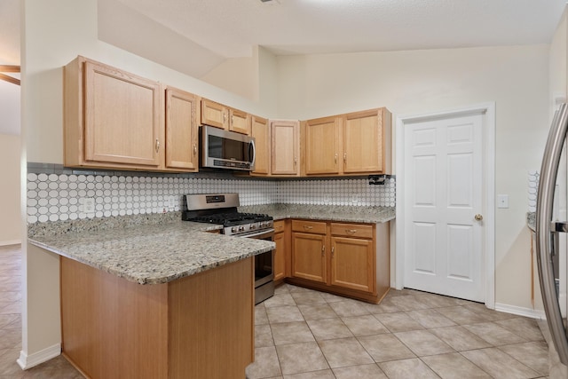 105 Steeplechase Dr, Crestview, FL 32539 - kitchen with appliances with stainless steel finishes, lofted ceiling, a peninsula, light brown cabinetry, and decorative backsplash