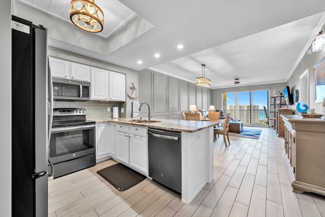 122 Seascape Dr Unit 1104, Miramar Beach, FL 32550 - kitchen featuring appliances with stainless steel finishes, crown molding, a sink, a peninsula, and wood tiled floors