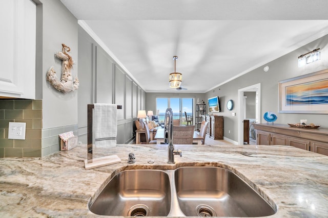 122 Seascape Dr Unit 1104, Miramar Beach, FL 32550 - kitchen featuring a sink, light stone countertops, crown molding, tasteful backsplash, and pendant lighting