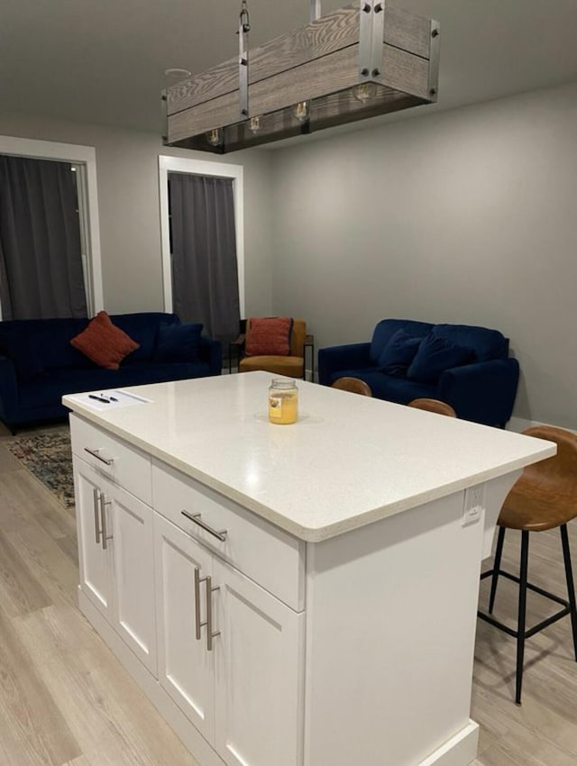 1200 N F St Unit A, Pensacola, FL 32501 - kitchen with light wood-type flooring, white cabinets, light countertops, and a kitchen island