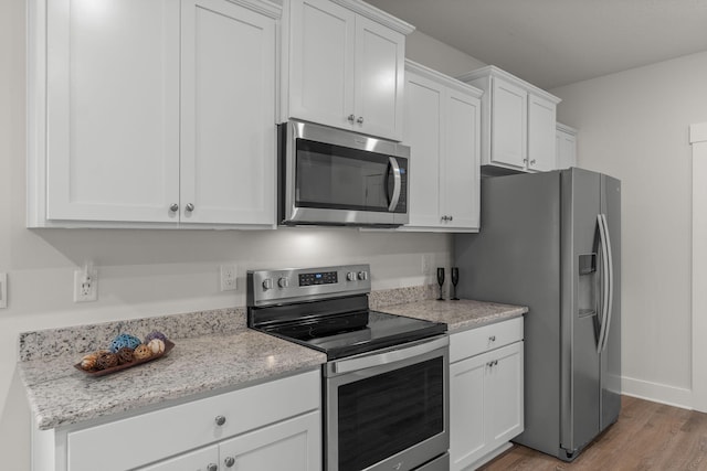 608 Champ Trl, Crestview, FL 32539 - kitchen featuring stainless steel appliances, light wood-style flooring, white cabinetry, and light stone countertops