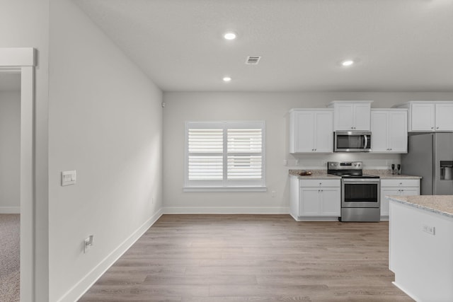 608 Champ Trl, Crestview, FL 32539 - kitchen featuring appliances with stainless steel finishes, white cabinets, recessed lighting, baseboards, and light stone counters