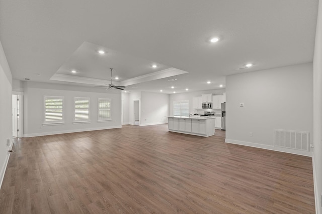 608 Champ Trl, Crestview, FL 32539 - unfurnished living room featuring a tray ceiling, baseboards, ceiling fan, recessed lighting, and light wood-style floors