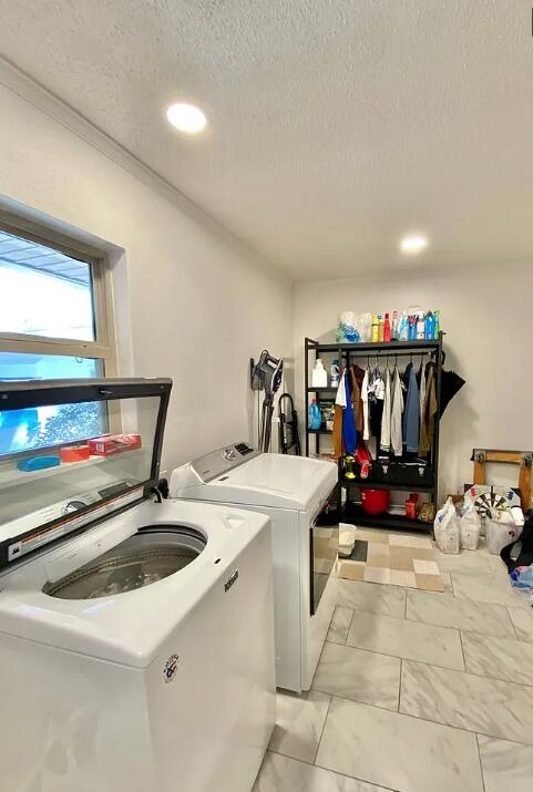 123 NW Sotir St, Fort Walton Beach, FL 32548 - washroom with washer and clothes dryer, a textured ceiling, recessed lighting, and light marble finish flooring
